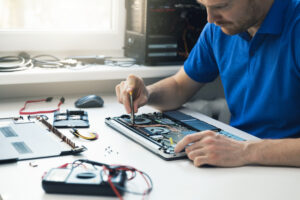 computer repair service – technician repairing broken laptop in office